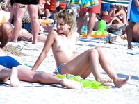 Due donne topless su una spiaggia sabbiosa affollata