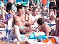 Due donne topless su una spiaggia sabbiosa affollata