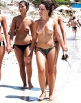 Two Nudists Step From the Surf Onto Wet Sand at the Shoreline