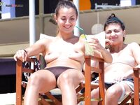 Striped Towel Across Her Lap on a Wooden Beach Lounger