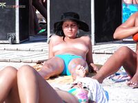 Fixing Her Straw Hat Between Yellow Loungers by the Blue Sea