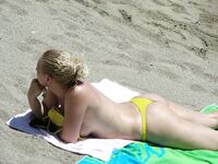 Su flor roja y una sonrisa natural en un paseo por playa topless