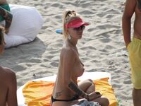Su flor roja y una sonrisa natural en un paseo por playa topless