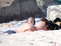 Sluneční brýle a klidná voda za opalováním na nudistické pláži