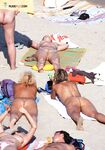 White Head Wrap and Striped Towels on a Sandy Nude Sunbathing Scene