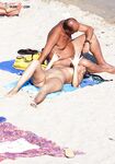 White Head Wrap and Striped Towels on a Sandy Nude Sunbathing Scene