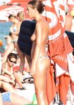 Braços atrás da cabeça num trecho movimentado de praia topless