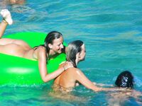 Three Nudists Laugh Together on a Bright Green Pool Float