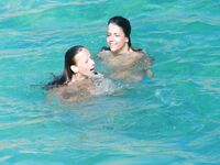 Three Nudists Laugh Together on a Bright Green Pool Float