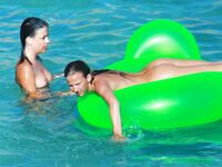 Three Nudists Laugh Together on a Bright Green Pool Float