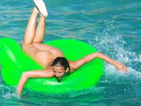 Three Nudists Laugh Together on a Bright Green Pool Float
