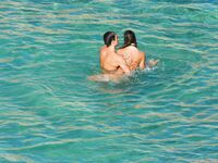Three Nudists Laugh Together on a Bright Green Pool Float