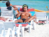 Gold Necklace and Striped Lounger Topless Sunbathing by Calm Water