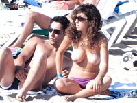 Topless procházka po břehu s potištěnou taškou kolem plavců
