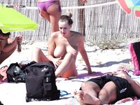 Topless procházka po břehu s potištěnou taškou kolem plavců