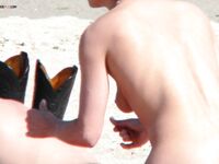 Un momento tranquillo sulla sabbia chiara condiviso da due adulti in spiaggia nudista