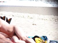 Un momento tranquillo sulla sabbia chiara condiviso da due adulti in spiaggia nudista