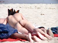 Un momento tranquillo sulla sabbia chiara condiviso da due adulti in spiaggia nudista