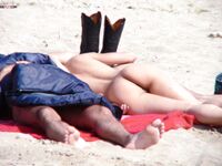 Un momento tranquillo sulla sabbia chiara condiviso da due adulti in spiaggia nudista