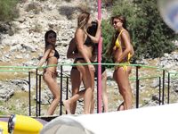 Pelle lucida al sole in slip gialli sulla riva di una spiaggia topless