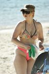 Pelle lucida al sole in slip gialli sulla riva di una spiaggia topless