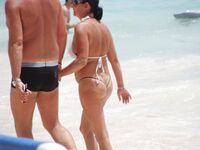 Pelle lucida al sole in slip gialli sulla riva di una spiaggia topless