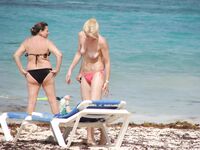 Pelle lucida al sole in slip gialli sulla riva di una spiaggia topless
