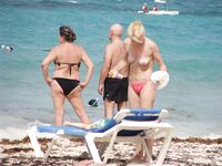 Pelle lucida al sole in slip gialli sulla riva di una spiaggia topless