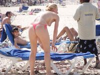 Pelle lucida al sole in slip gialli sulla riva di una spiaggia topless