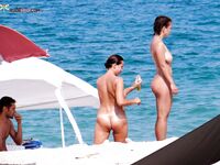Si raccoglie i capelli scuri al mare su una tranquilla spiaggia nudista