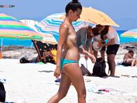 A Couple Leaves Turquoise Shallows Near a Striped Umbrella on a Nude Beach