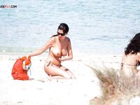 Przegląda plażowe torby na spokojnej plaży nudystów