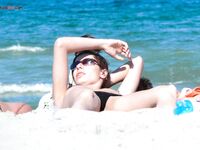 Gafas oscuras y arena cálida en un primer plano de tomar el sol desnudo