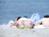 Cheveux roux et bas bleus sur une plage topless
