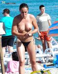 Cerchi alle orecchie e teli su una riva topless affollata