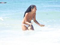 Rindo de braços abertos na orla rochosa topless
