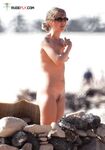 Folded Towel in Hand Behind Sun-Bleached Nude Beach Rocks