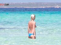 Folded Towel in Hand Behind Sun-Bleached Nude Beach Rocks