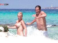Folded Towel in Hand Behind Sun-Bleached Nude Beach Rocks