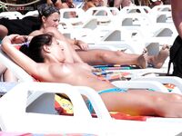 Zastavená s rukama za krkem na rušné topless pláži