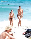 Three Topless Women in Pink, White and Red Bikini Bottoms by the Sea