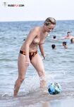 Rizos y gafas oscuras sobre una toalla en una concurrida playa topless