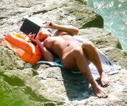 Nude Sunbathing Against a Wooden Windbreak on Warm Sand
