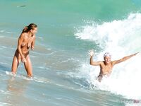 Esce dal mare basso sulla sabbia chiara per un'abbronzatura nuda
