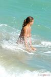 Esce dal mare basso sulla sabbia chiara per un'abbronzatura nuda