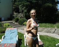 Tranquila con las piernas cruzadas en un banco a rayas junto a la piscina