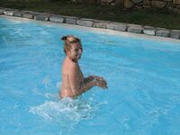 Tranquila con las piernas cruzadas en un banco a rayas junto a la piscina