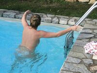 Tranquila con las piernas cruzadas en un banco a rayas junto a la piscina