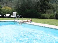 Tranquila con las piernas cruzadas en un banco a rayas junto a la piscina