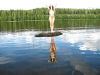 Wasser spritzen vom halb versunkenen Baumstamm im Waldsee